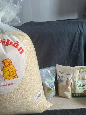 Hamsterpaket med bur, spån och foder - Säljer ett hamster med stor blå bur, påse kutterspån, flera påsar hamsterfoder och tillbehör som matskålar, sandbad, hus och leksaker i trä. Perfekt för dig som vill starta med hamster och få allt på en gång.