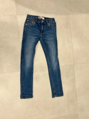 Levi's 512 Slim Taper jeans blå - Snygga blå jeans från Levi's modell 512 Slim Taper. Jeansen har smal passform med avsmalnande ben och klassiska fem fickor. Tillverkade i denim med kontrastsömmar och knappgylf. Perfekta för en trendig och avslappnad look.