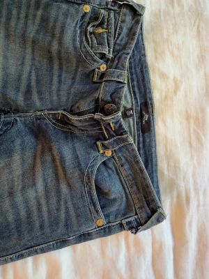 Blå low rise flare jeans Joey/True religion  - Säljer ett par blå jeans i modellen low rise flare från Joey. Aldrig använt och är i storlek 26