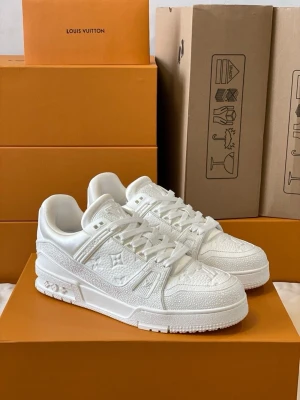 Helvita sneakers - Stilrena helvita sneakers från med präglade monogramdetaljer och texturerad ovandel. Skorna har klassisk låg siluett, vita skosnören och robust sula. Perfekta för dig som vill ha en clean och exklusiv look.