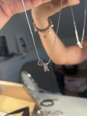 silverhalsband med hjärta och bokstav K. - säljer detta halsband med ett litet hjärta och bokstaven K. aldrig haft på mig det och säljer pågrund av att jag använder guld smycken.💓