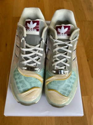 adidas ZX 6000 XZ Inside Out sneakers - Unika sneakers från adidas med en mix av beige, mintgrönt och gult. Modellen har tydliga inslag av mesh, mocka och transparenta detaljer samt de klassiska tre ränderna på sidan. Tungan har rödvit adidas-logga och sulan är i ljusgult. Perfekt för dig som gillar statement-skor.