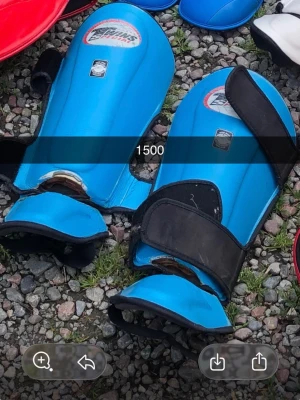 Blå benskydd med kardborreband - Säljer ett par blå benskydd med svarta kardborreband och vit logga på ovansidan. Perfekta för träning eller match inom olika sporter där skydd behövs. Lätta att ta på och av tack vare de breda banden.