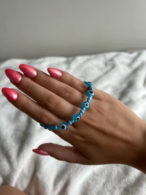  armband med evil eye-pärlor - Säljer ett blått armband med små evil eye-pärlor , trädda på en tunn kedja i silverfärg. Armbandet har justerbar längd med en enkel kedjelåsning. Perfekt för dig som gillar unika och trendiga accessoarer.💕