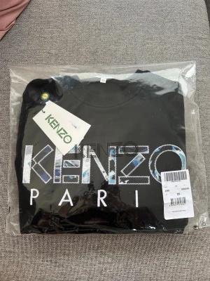 Kenzo tröja - nyskick - Säljer en svart Kenzo tröja. Tröjan är i nyskick, använd 1 gång. Tillhörande påse, lapp och kvitto från köpet finns kvar. Strl XS.