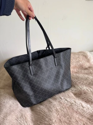 By Malene Birger väska - INTRESSEKOLL! Perfekt att lägga dator och skolböcker i! Säljer min fina malene birger väska i mellanstorleken som är svart och grå mönstrad. Använt skick, handtagen är lite slitna och finns lite fläckar innuti. Köptes för 3200kr. Dustbag kommer med!
