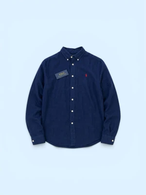 Mörkblå linneskjorta från Polo Ralph Lauren - Klassisk mörkblå skjorta i linne från Polo Ralph Lauren med knappslå och vit knappdetalj. Skjortan har lång ärm och ikonisk röd logga broderad på bröstet. Perfekt för en stilren och avslappnad look.