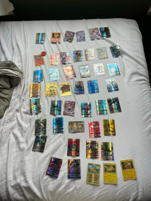Samling Pokémonkort holografiska - Stor samling Pokémonkort med flera holografiska och färgglada kort. Blandade motiv och karaktärer från Pokémonvärlden, vissa med guldkant och olika färger. Perfekt för dig som vill utöka din samling eller börja samla Pokémonkort.