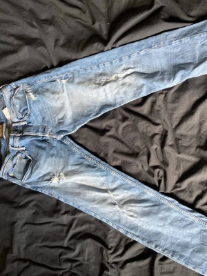 Ljusblå replay jeans - Säljer ett par ljusblå jeans . Jeansen har klassisk femficksmodell, dragkedja och knapp i midjan samt slitna detaljer framtill och på bakfickan. Perfekta för en avslappnad och trendig look.