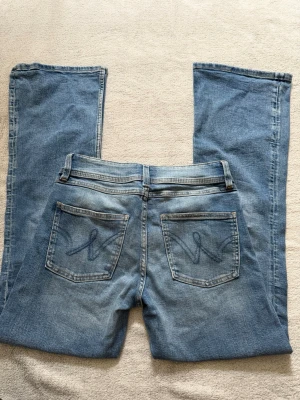 Blå bootcut jeans med broderade fickor från Gina Tricot - Jag säljer ett par ljusblå bootcut jeans med snygga broderade detaljer på bakfickorna. 