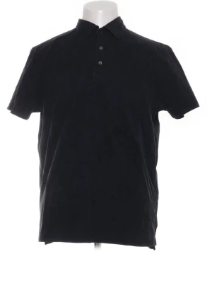 Suitsupply pikétröja - En stilren svart pikétröja med korta ärmar och krage. Tröjan har tre knappar framtill och är tillverkad i ett mjukt material som passar perfekt till jeans eller shorts. Enkel och tidlös design som funkar till många olika stilar.