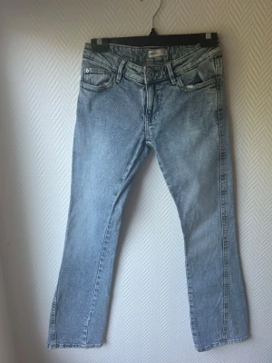 Ljusblå smått utsvängda jeans med broderade fickor - Ljusblå jeans med smått utsvängd passform och klassisk femficksdesign. Jeansen har snygga broderade detaljer på bakfickorna och en något tvättad look. Perfekta för en avslappnad stil.