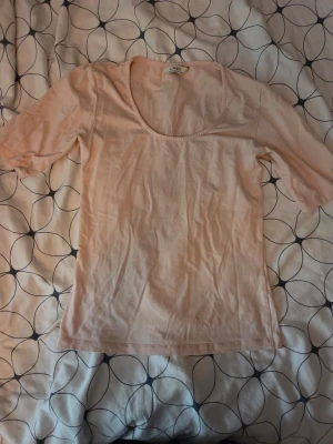Ljusrosa topp från Lindex - Söt ljusrosa topp från Lindex med rundad urringning och korta ärmar. Tillverkad i mjuk bomull, perfekt för en enkel och stilren look. Passar bra till jeans eller kjol.
