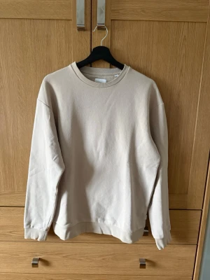 Beige sweatshirt från Jack & Jones - En stilren beige sweatshirt från Jack & Jones med rund halsringning och ribbade muddar vid ärmslut och nederkant. Tröjan är i mjukt material och har en avslappnad passform, perfekt för en chill look.