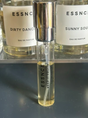 ESSNCE Keep It Fruity Eau de Parfum - ESSNCE Keep It Fruity Eau de Parfum i en smidig glasflaska med silverfärgad spraykork. Flaskan är cylinderformad och genomskinlig, vilket visar den ljusgula parfymen inuti. Modern och stilren design, perfekt för dig som gillar fruktiga dofter.