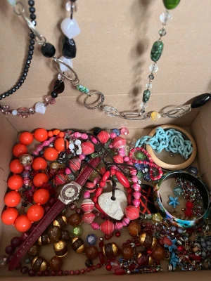 Låda med blandade färgglada smycken - En mixad låda med olika smycken som halsband, armband och pärlor i flera olika färger! Har både hela halsband, armband och dessutom lösa pärlor! Super användbart för någon som gillar att pyssla eller skapa smycken!