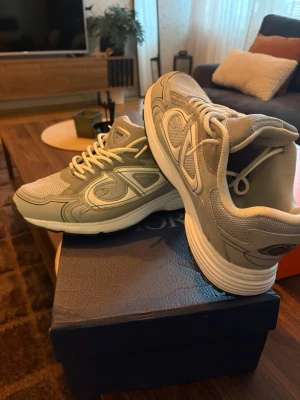 Beige sneakers med mesh och detaljer - Snygga beige sneakers med meshpaneler och syntetiska detaljer. Skorna har en chunky vit sula och C. D-logga på hälen. Perfekta för dig som gillar en sportig och trendig look. Skön passform och klassisk snörning framtill.