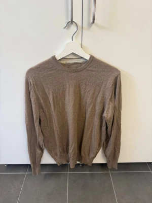 Brun Stenströms tröja i Merinoull, Stl L - En enkel och stilren beige stickad tröja med rund halsringning och långa ärmar. Tröjan har ribbade muddar vid ärmslut och nederkant. Perfekt att matcha med jeans eller kjol för en avslappnad look.