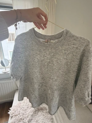 Ljusgrå stickad tröja - Mysig ljusgrå stickad tröja med rund halsringning och ribbade muddar. Tröjan har en avslappnad passform och är perfekt för lager på lager. Materialet känns mjukt och behagligt mot huden.🩶