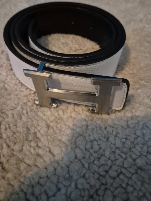 Vit bälte - Ett bälte som passar bra med många outfits, ett silver H som spänne, storleken är 110cm
