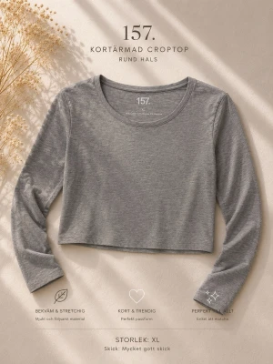 Grå croppad långärmad topp 157 - En enkel och stilren grå croppad långärmad topp från 157. Tillverkad i en mjuk blandning av bomull, viskos och elastan som ger en skön och stretchig känsla. Perfekt till jeans eller kjol för en avslappnad look.