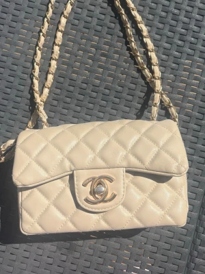 Beige väska  med kedjerem - Snygg  beige handväska. Perfekt för dig som gillar tidlös och elegant design.