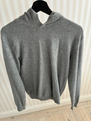Grå hoodie i mjukt material - En stilren grå hoodie med huva och långa ärmar. Tillverkad i ett mjukt och bekvämt material som känns skönt mot huden. Perfekt för dig som gillar en enkel och clean look. Inga synliga loggor eller tryck, bara klassisk och tidlös design. Knappt använd och passar om man har M också