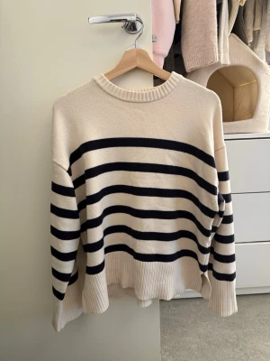 Zara stickad tröja - Säljer denna fina stickad tröja från Zara. Den är Mysig och har en stilren modell med ribbad hals och slits vid nederkanterna. Perfekt till jeans, kjol eller över en skjorta. Snygg oversized/ledig passform.