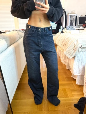 Mörkblå raka jeans med hög midja - Säljer ett par mörkblå jeans med hög midja och raka ben. Jeansen har klassiska fem fickor och stängs med knapp och dragkedja. Materialet är denim och passformen är avslappnad och trendig.