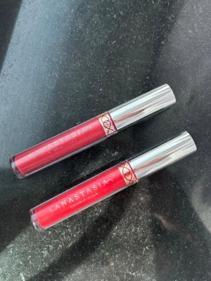 2x Anastasia Beverly Hills Liquid Lipsticks - Säljer två flytande läppstift från Anastasia Beverly Hills. Den ena nyansen är den klassiskt röda "American Doll", medan den andra har tappat sin färglapp undertill men går i en matchande röd tone.  Märke: Anastasia Beverly Hills  Produkt: Liquid Lipstick  Nyanser: American Doll + 1 okänd röd nyans (lappen saknas undertill)  Skick: Swatchade / endast testade enstaka gång. Skickas självklart rengjorda och spritade/sanerade! Säljes helst tillsammans som ett set. #anastasiabeverlyhills #abh #liquid