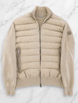 Beige cardiganjacka från Moncler - Snygg beige cardiganjacka från Moncler med quiltad front och stickade ärmar. Jackan har dragkedja framtill, två fickor med dragkedja och ribbade muddar. Perfekt för lager på lager och en clean look.