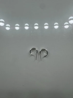 Små silvriga hoops örhängen - Säljer ett par små, klassiska hoops i silverfärgad metall. De har en enkel och stilren design som passar till det mesta. Perfekta för dig som gillar minimalistiska smycken och vill ha något som funkar varje dag.