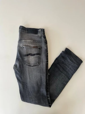 Grå jeans från nudie med snygga fades - Säljer ett par sjukt snygga nudie jeans med snygga fades och märken alla märken och fades syns på bilderna och det finns symärken lite här och var till exempel på framfickorna, lite vid bakfickorna och sen ett litet lagat hål vid skrevet. De är 30W och 32L vid frågor om till exempel mått är det bara att säga till Mvh Olof!