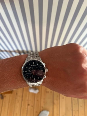 Citizen silverfärgad klocka - Stilren klocka från Citizen med silverfärgad länk i metall och svart urtavla. Klockan har datumvisning, flera små urtavlor och tydliga markeringar. Perfekt accessoar för dig som gillar klassisk och tidlös design.