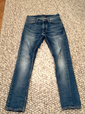 Nudie jeans grim Tim  - Snygga blå slim fit jeans med lätt slitna detaljer och klassisk femficksdesign. Jeansen har normal midja och raka ben.