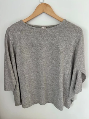 Ljusgrå/beige lös topp med trekvartsärm - En enkel och stilren ljusgrå topp med lös passform och trekvartsärmar. Tillverkad i ett mjukt material som känns skönt mot huden. Perfekt till jeans eller kjol för en avslappnad look. Aldrig använd, lapp kvar
