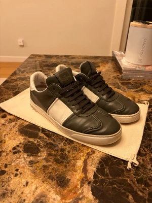 Valentino flycrews - Snygga sneakers från Valentino i svart och vitt läder med svarta mörkgrön och vit sula. Klassisk låg modell med diskret logga på plösen och stilrena detaljer. Perfekta för dig som vill ha en clean och exklusiv look. Hör gärna av dig vid funderingar!