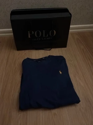 Mörkblå tröja från Polo Ralph Lauren - Snygg mörkblå tröja från Polo Ralph Lauren i slim fit-modell, tillverkad i mjuk pima bomull. Tröjan har rund halsringning och den klassiska broderade loggan på bröstet. Perfekt för en stilren och enkel look.