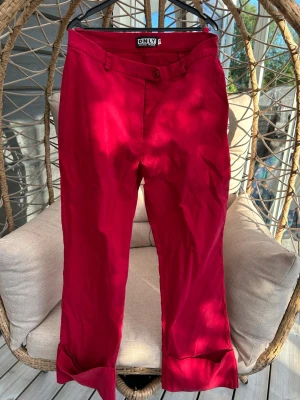 Chinos strl. 38 - Röda chinos från ONLY med klassisk passform och uppvikta benslut. Byxorna har knapp och dragkedja framtill samt bälteshällor. 