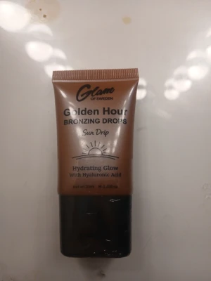 Golden Hour Bronzing Drops Sun Drip - Golden Hour Bronzing Drops Sun Drip från Glame of Sweden ger en återfuktande glow med hyaluronsyra. Flytande bronzer i en brun tub med svart lock, perfekt för att skapa en solkysst look. Innehåller 20 ml.