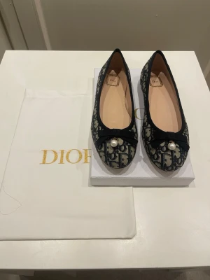 Dior ballerinaskor med pärldetalj - Snygga ballerinaskor från Dior som köptes förra året i september. Dom är i nästan ny skick och har inga repor eller skador eftersom jag inte haft dom utomhus💕. För mer frågor hör gärna av dig. Kvitto följer med och dustbag💕