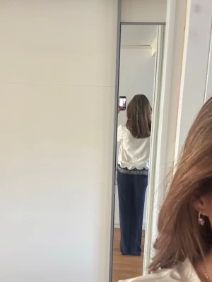 Vit Tshirt med spetsdetaljer - Säljer en söt vit kortärmad topp. Toppen har svart spets längs nederkanten som ger en elegant touch. 