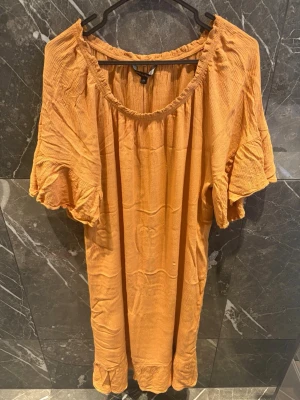 Orange klänning med volangärmar - Jättefin orange klänning i storlek M. Fin och luftig modell med volangärmar och band i midjan som kan knytas för att anpassa passformen. Väldigt fin färg och perfekt till vår och sommar. I mycket bra skick.