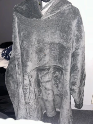 Grå oversized fleecehoodie - Supermjuk och mysig grå oversized hoodie i fleece med stor ficka framtill och huva. Perfekt för chill hemma eller när du vill vara extra bekväm. Materialet är fluffigt och värmande, och modellen är lös för maximal komfort.