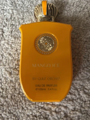 Mango Ice Eau de Parfum 100ml HELT NY PROVAT EN GÅNG - Fräsch parfym med doft av mango i en snygg, klargul flaska med gulddetaljer och dekorativt lock. Flaskan rymmer 100 ml och har en unik, modern form som sticker ut i badrumshyllan. Perfekt för dig som gillar fruktiga och exotiska dofter. Passar båda kön