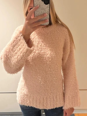 Ljusrosa fluffig stickad tröja - Supermjuk och fluffig stickad tröja i ljusrosa färg. Tröjan har en avslappnad passform, rund halsringning och vida ärmar. Perfekt för dig som gillar mysiga och trendiga plagg. Materialet känns lurvigt och ger en cozy vibe.