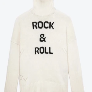 Vit polotröja med text - Säljer en vit polotröja med texten 'Rock & Roll' i svart. Från Zadig! Tröjan har en hög krage och långa ärmar, perfekt för kyligare dagar. Den är både stilren och trendig, idealisk för dig som vill sticka ut.