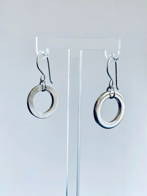 Silvriga cirkelörhängen i stål - Snygga örhängen i form av enkla, silvriga cirklar. De är tillverkade i stål och har en minimalistisk design med krokar för enkel användning. Perfekta för dig som gillar stilrena accessoarer med en modern touch.