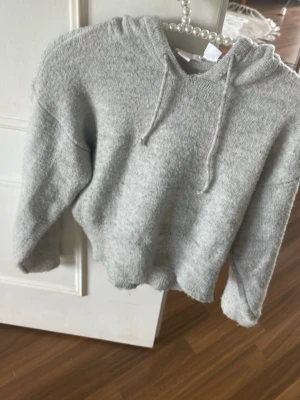 Grå mjuk hoodie med huva - Säljer en supermjuk och fluffig grå hoodie med huva och dragsko. Hoodien har avslappnad passform, långa ärmar och ribbade muddar. Perfekt för dig som gillar en enkel men cozy stil.