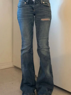 Blå bootcut jeans med slitning - Säljer ett par blå bootcut jeans med slitning på låret och snygga detaljerade bakfickor. Jeansen är ifrån gina tricot och i stl s, dem är lite slitna nere vid hälarna men inget man tänker på☺️
